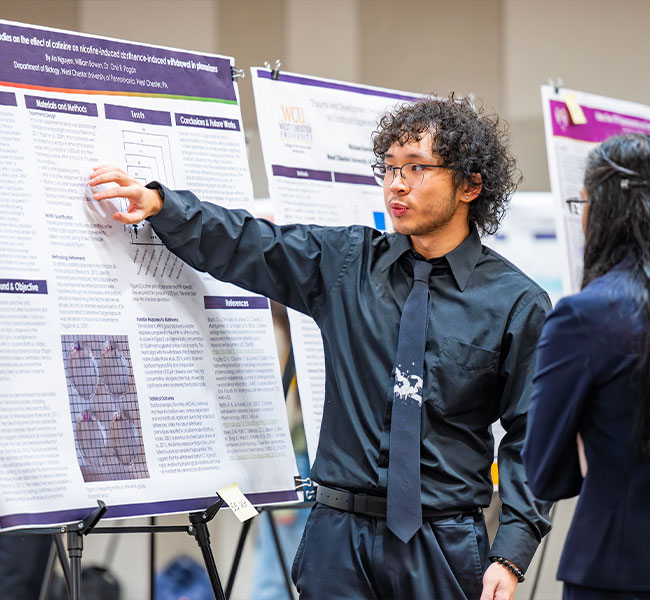 two people look upon a poster board with research and graphs