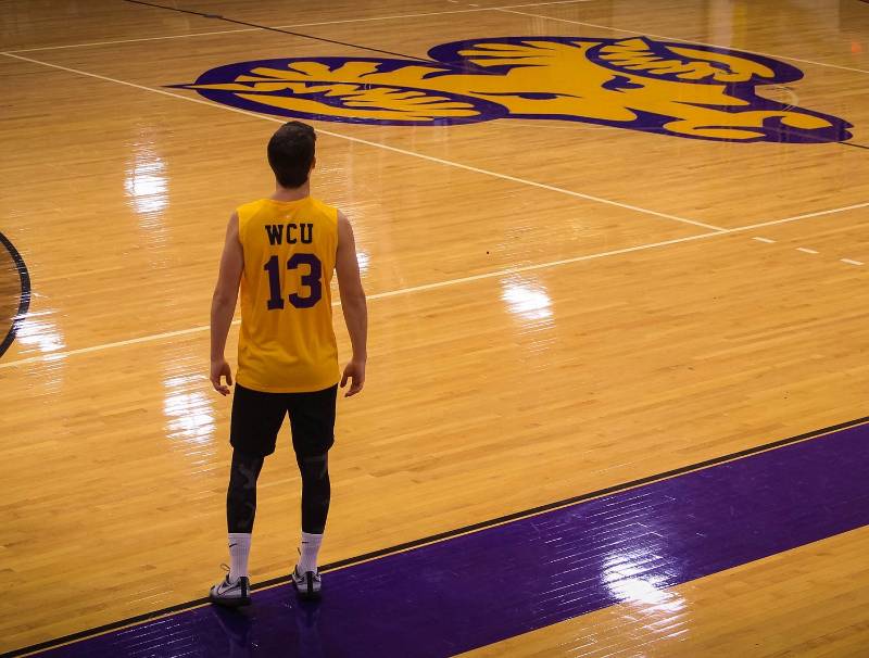 Student standing next to playing court in WCU jersey