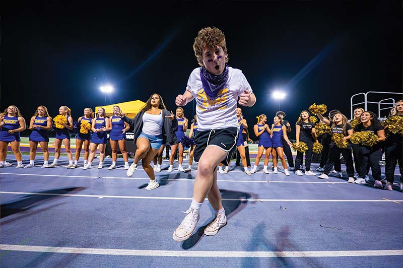 A student wearing WCU gear dances in the middle of a dance circle made of WCU Cheerleaders and the WCU Dance Team