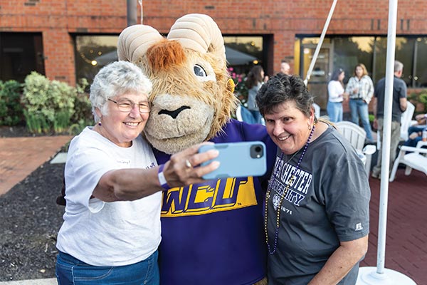 Two older people smile and pose for a selfie with Rammy
