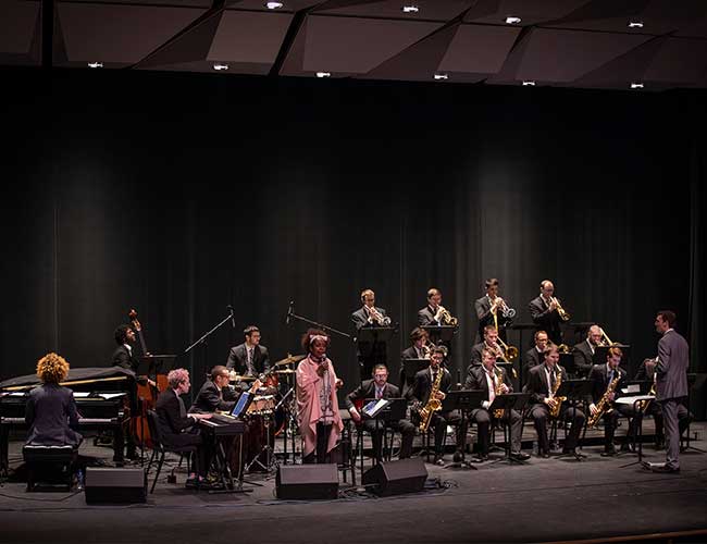 Wide shot of jazz ensemble including piano and vocalist.