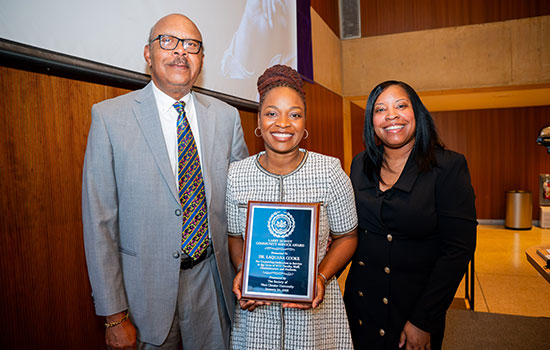 Female holding up an award from the soceity with 2 others